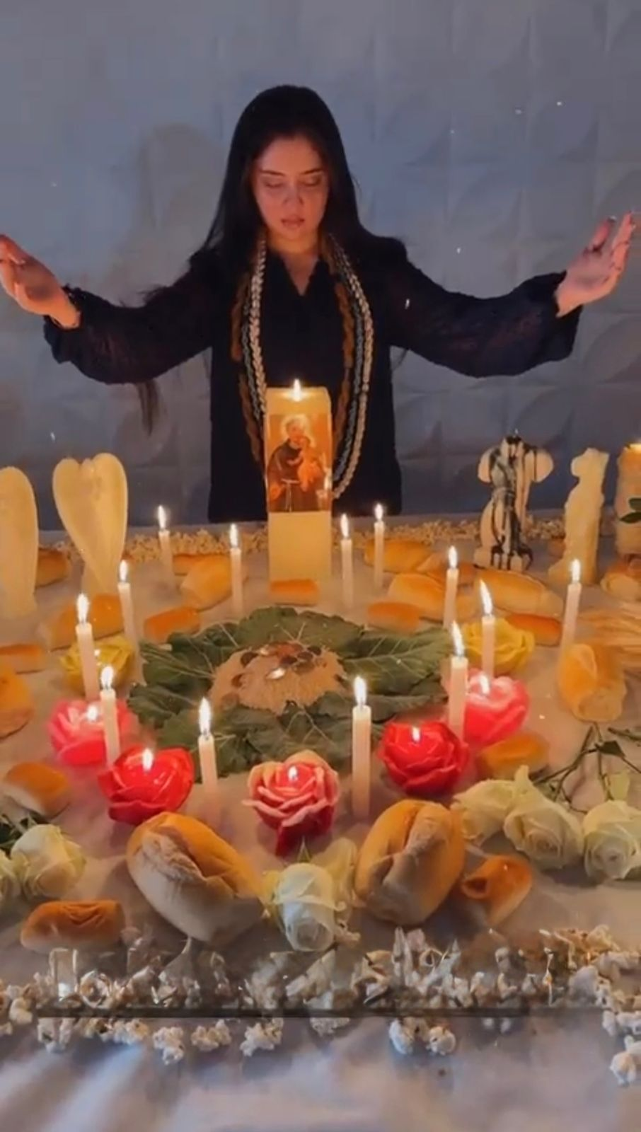 Mãe Esmeralda realizando ritual espiritual de amarração amorosa com velas e oferendas